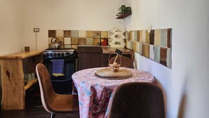 A rustic kitchen with a wooden ceiling, a gas stove, a sink, and a table with chairs. - Cabaña Jacuzzi Interior (San Alfonso)