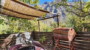 An outdoor patio with a wooden deck, a barbecue grill, and a covered seating area with a table and chairs. - Cabaña Jacuzzi Interior (San Alfonso)