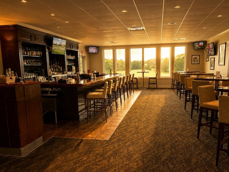 A bar area with a long counter, multiple chairs, and a carpeted floor.