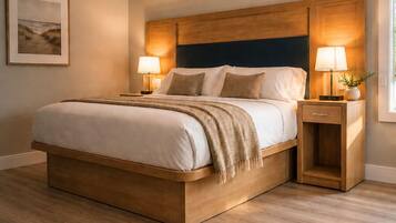 A bedroom with a wooden bed, two bedside tables with lamps, a framed picture on the wall, and a window with curtains.