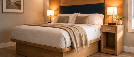 Un dormitorio con una cama de madera, dos mesitas de noche con lámparas, un cuadro enmarcado en la pared y una ventana con cortinas.