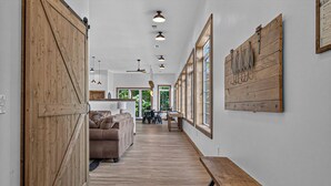 Un hall d’entrée spacieux avec un plancher en bois, une porte coulissante de style grange, un banc et, au fond, un coin repas.