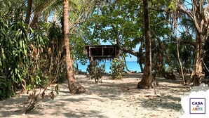 A beach with palm trees and a wooden structure in the background. - Oceanfront Artistic Escape in Cabuya (Cabuya)