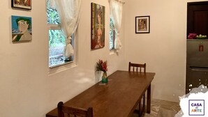 A dining area with a wooden table and chairs, a vase with flowers, and artwork on the walls. - Oceanfront Artistic Escape in Cabuya (Cabuya)