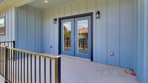A building with a blue exterior, a double door with glass panels, and a small porch area with a metal railing. - Quiet Hill Country Home: 1 Mi to Lake LBJ Access! (Granite Shoals)