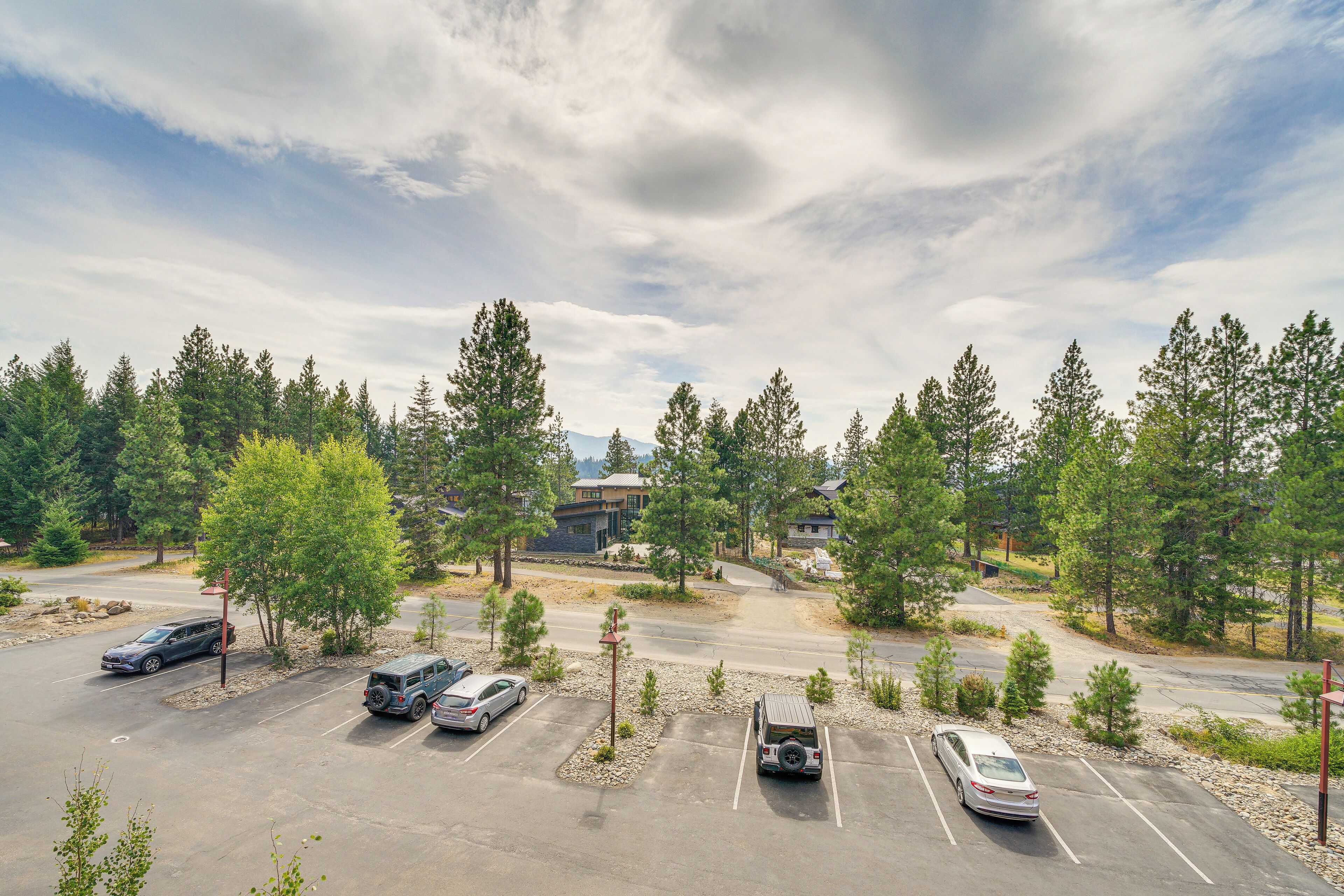 A parking lot with several cars, surrounded by trees and buildings in the background.