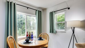 A dining area with a round wooden table, two chairs, a floor lamp, and curtains. - Private UP Escape Near Lake Superior (Pelkie)