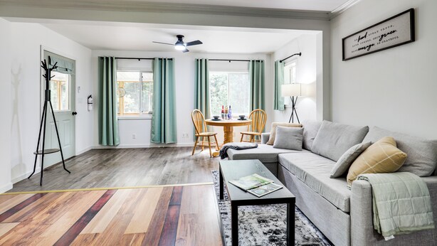 A living room with a sofa, coffee table, and a dining area with chairs and a table. - Private UP Escape Near Lake Superior (Pelkie)