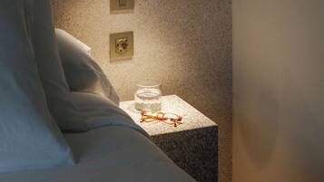 Un dormitorio con cama, mesita de noche y lámpara fijada en la pared.
