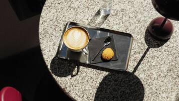 A round table with a cup of coffee, a spoon, and a small pastry.