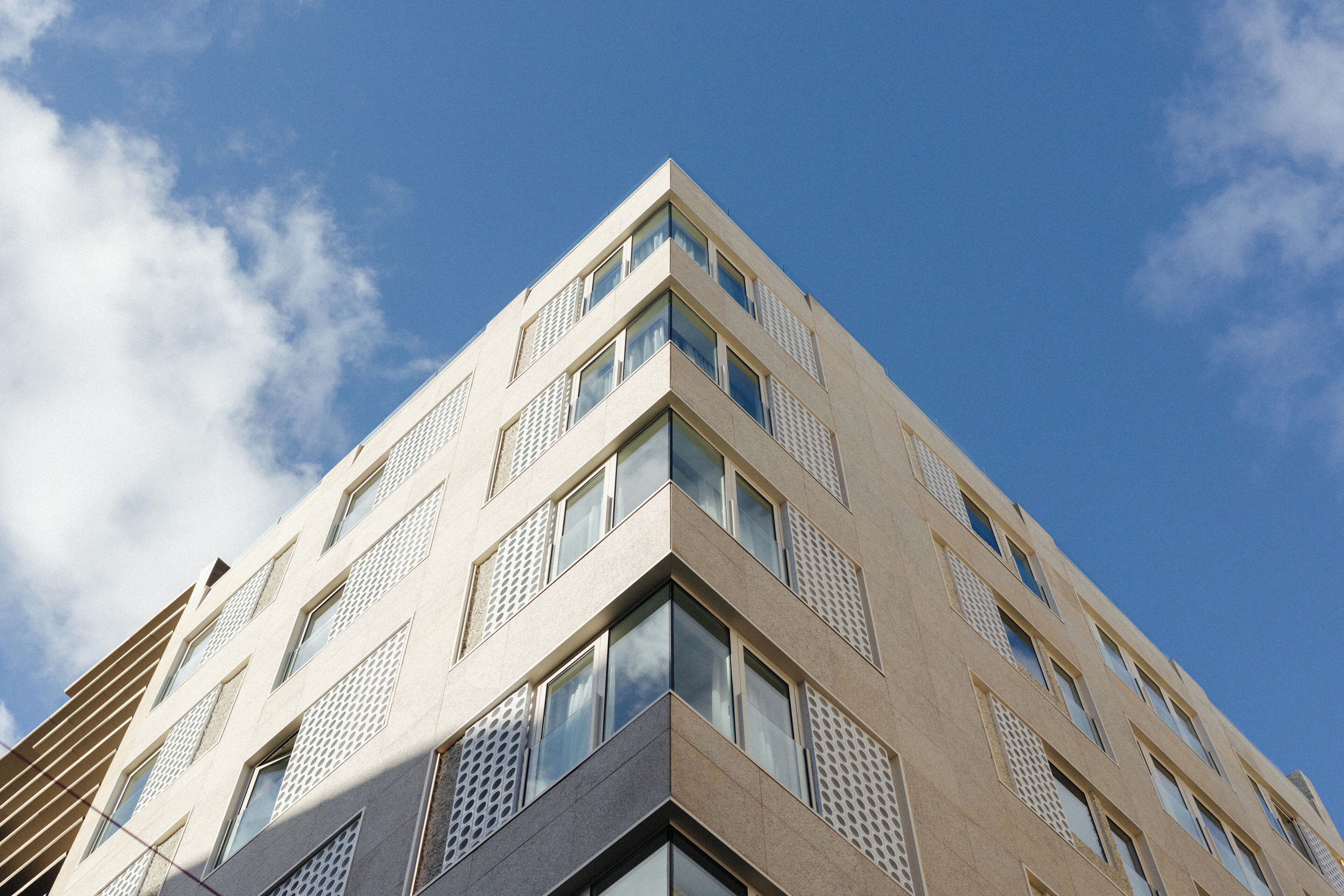Ein modernes Gebäude mit Eckblick, mit zahlreichen Fenstern und blauem Himmel.