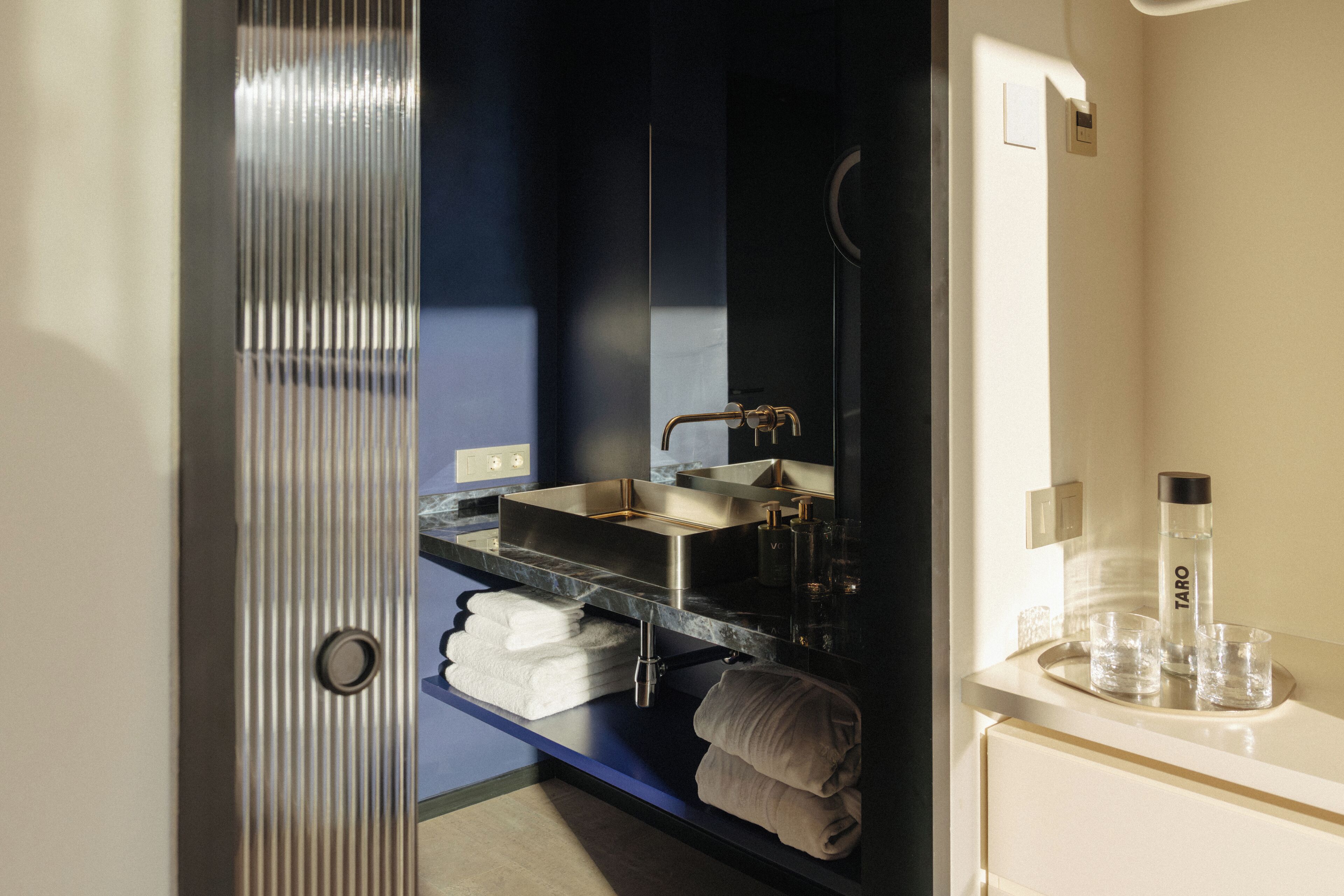 A modern bathroom with a large mirror, a sink, and a towel rack.