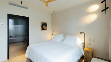 Une chambre à coucher avec un grand lit, un ventilateur de plafond, une lampe de chevet et une petite table de nuit en bois.