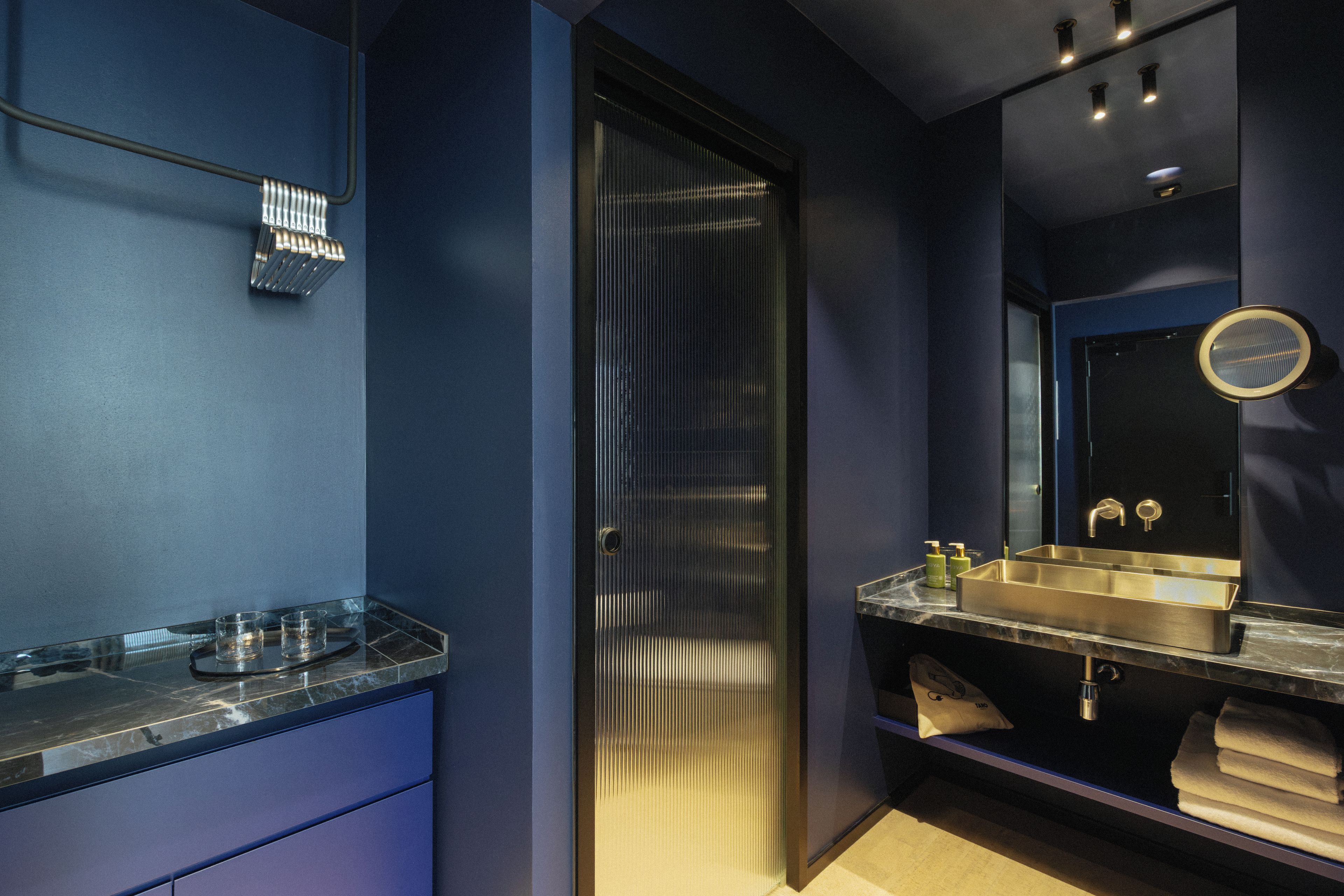 A modern bathroom with a large mirror, a sink, and a towel rack.