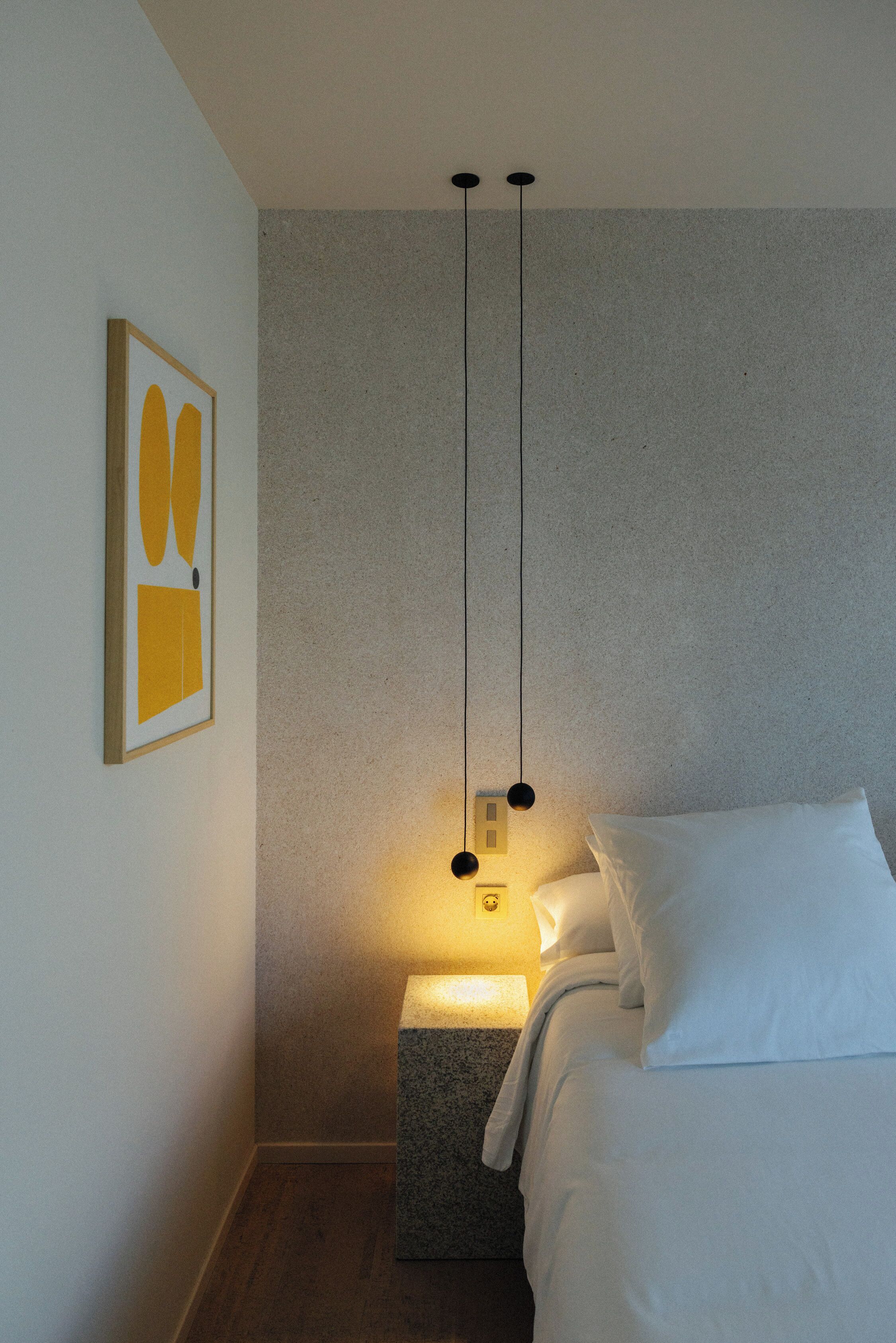 Ein Schlafzimmer mit einem Bett, einem Nachttisch, einer Wandlampe und einem gerahmten Bild.