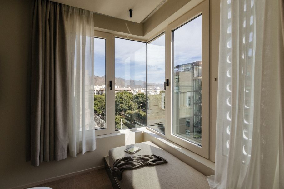 Un dormitorio con una ventana grande, una cama y vistas a la ciudad.