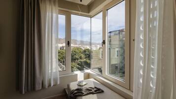 Un dormitorio con una ventana grande, una cama y vistas a la ciudad.