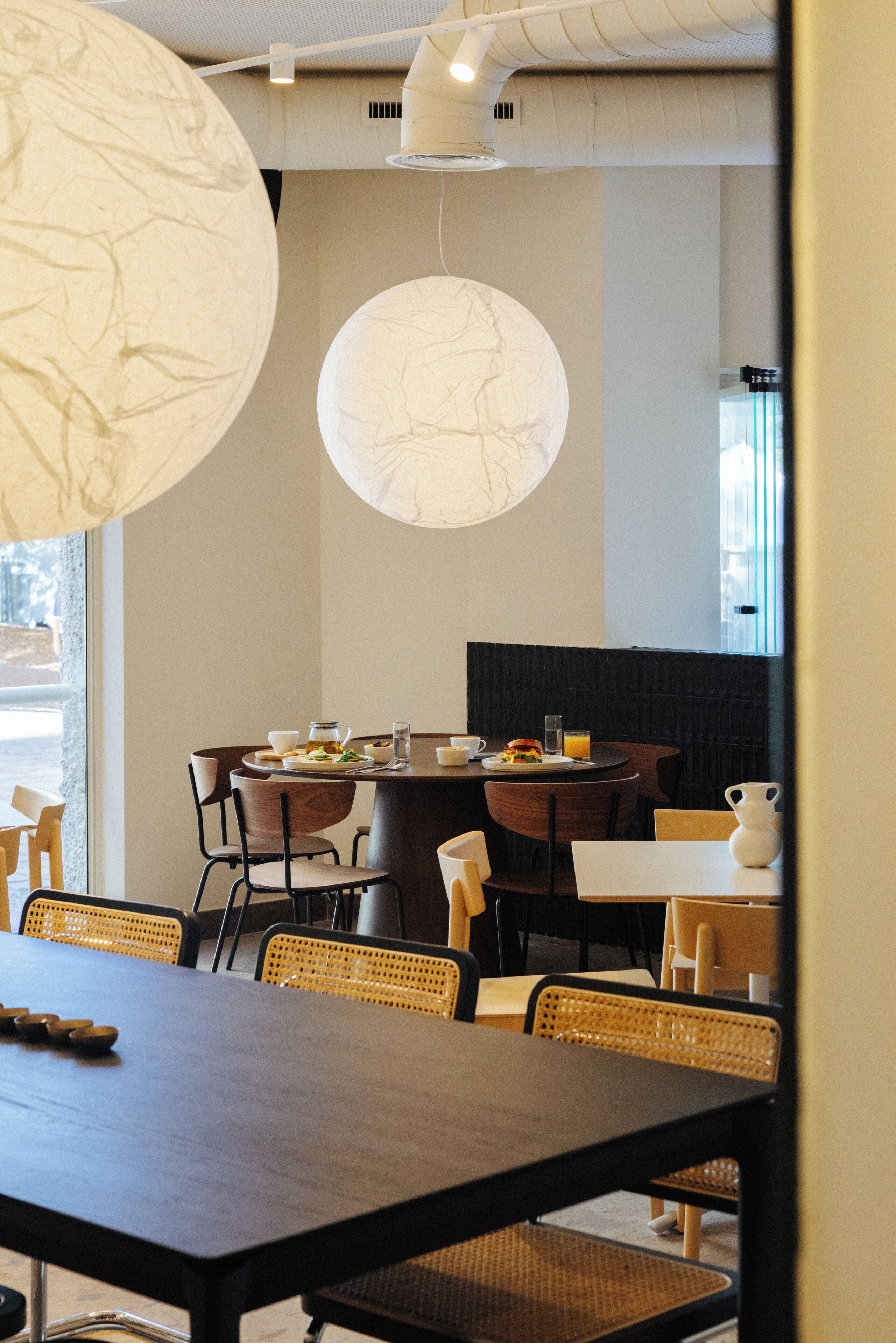 Un restaurant amb una taula rodona, caires i llums penjants.