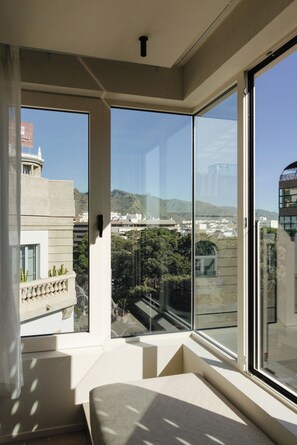 Una habitación con ventanas amplias, vistas a un paisaje urbano y un balcón.