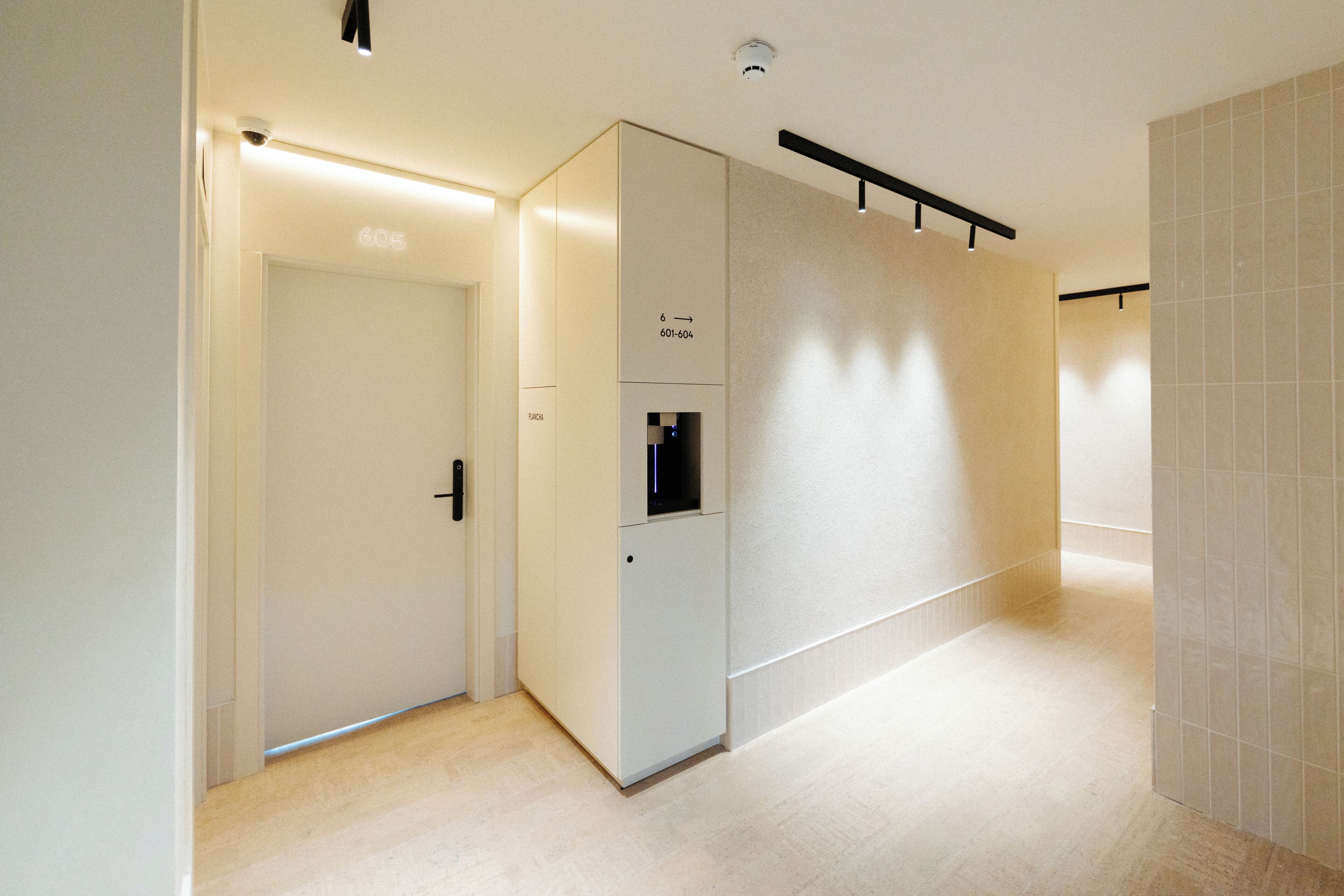 A hallway with a door, a vending machine, and a wall-mounted light fixture.
