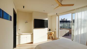 A hotel room with a bed, a desk, a chair, a TV, and a balcony with a view.