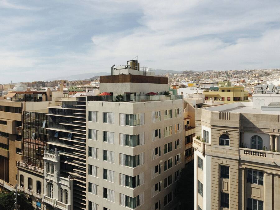 Un edificio de varios pisos con terraza en la azotea, ventanas grandes y un estilo arquitectónico moderno.