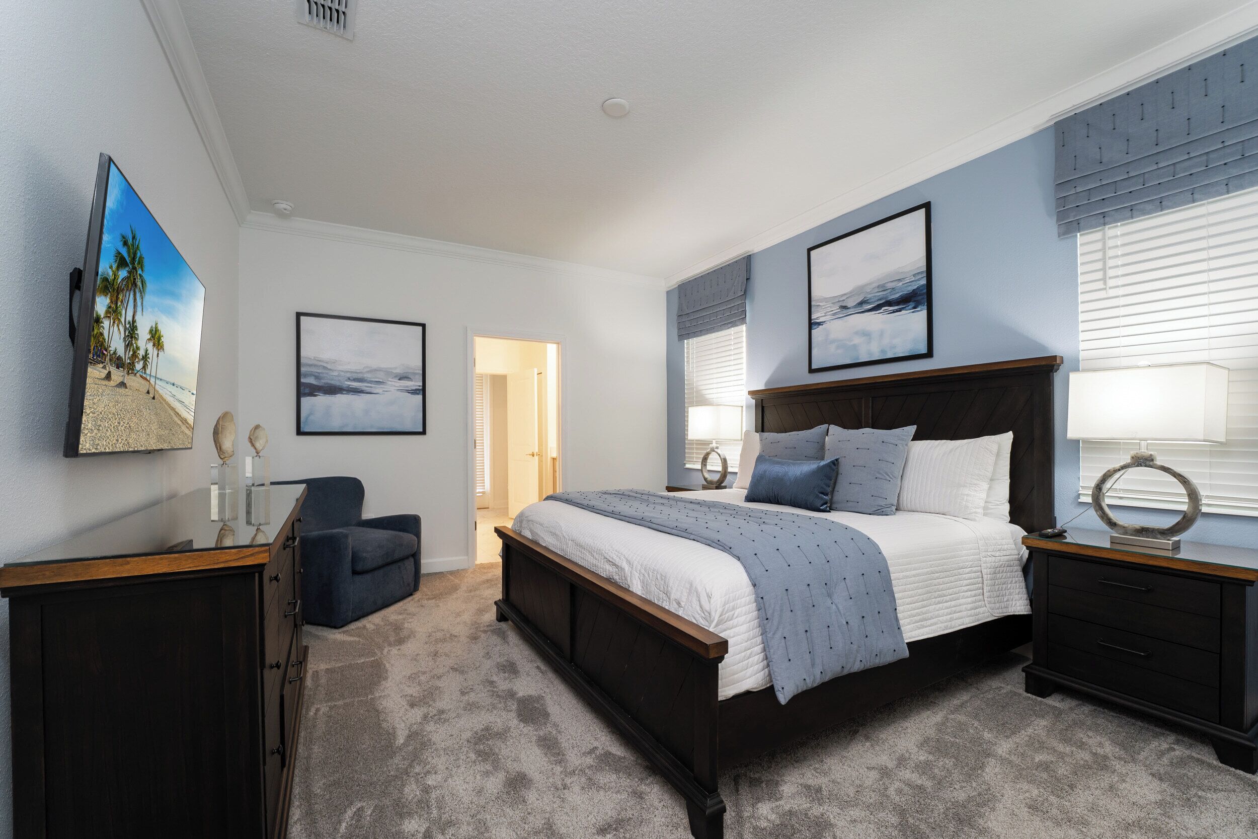 Ein Schlafzimmer mit Bett, Sessel, Kommode und Bildern an der Wand.