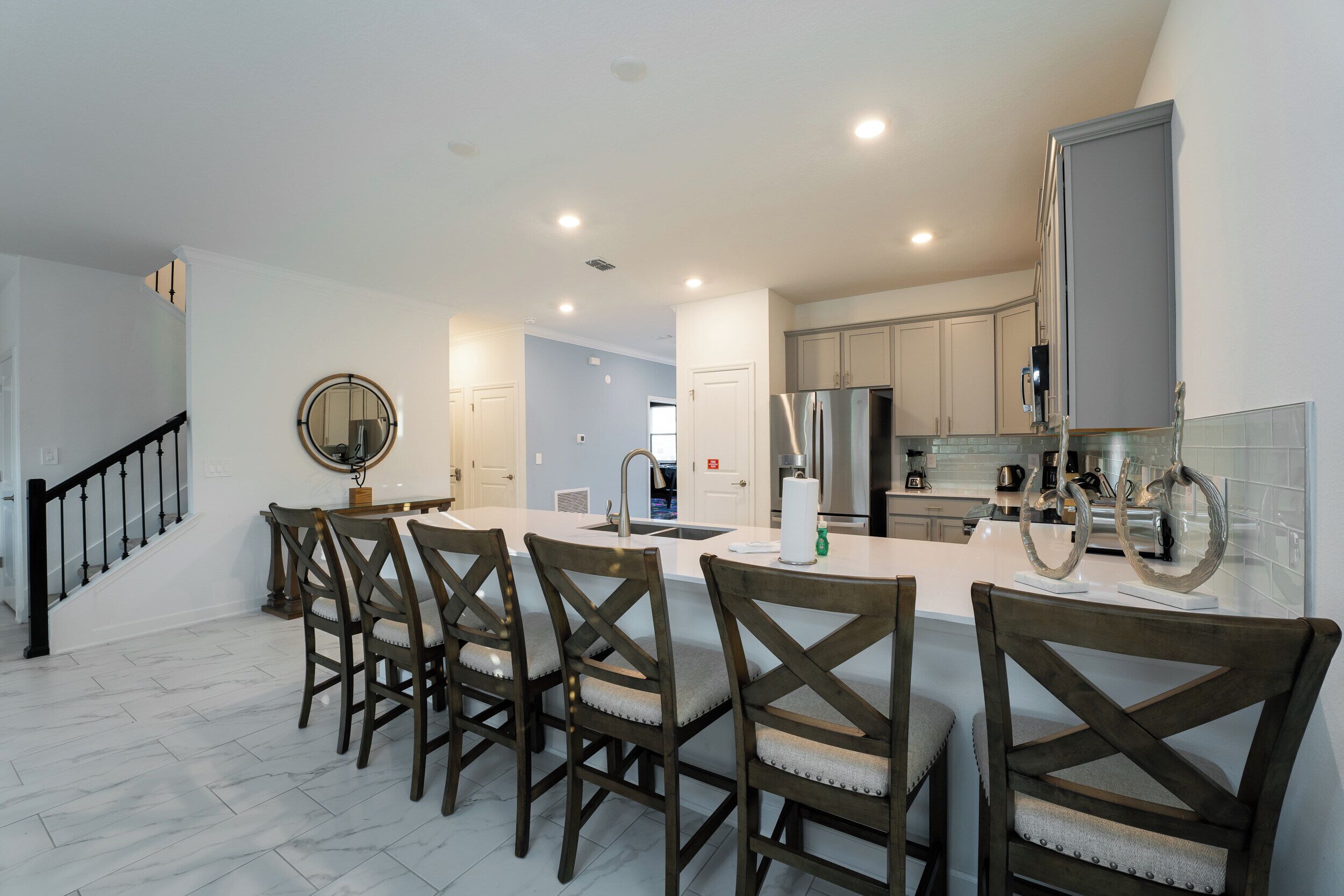Una cocina moderna con una isla central, electrodomésticos integrados y un comedor con sillas de madera.