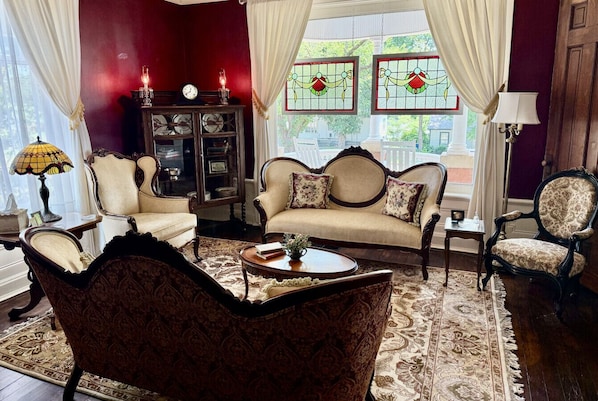 Un salon traditionnel avec un canapé, des fauteuils, une table basse et un meuble.