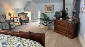 Une chambre à coucher avec un lit, une commode, une chaise, une lampe et une plante en pot.