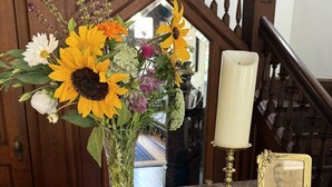 Une table en marbre ornée d’un vase de fleurs, d’une bougie, d’une photographie encadrée et d’un carnet ouvert avec un stylo.