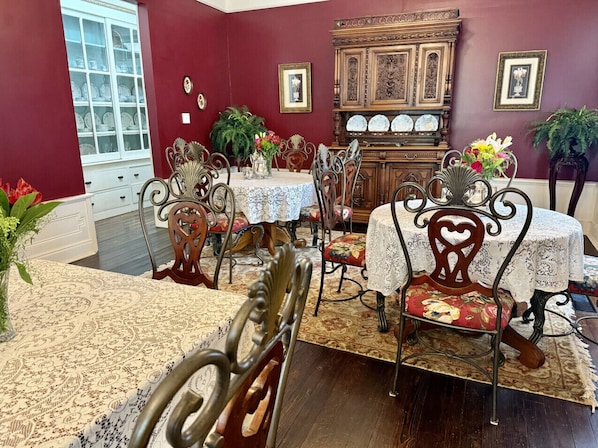 A dining area with a red wall, a wooden cabinet with dishes, and a window with a view.