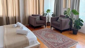 Ein Hotelzimmer mit einem Bett, zwei Sesseln, einem großen Teppich und Zimmerpflanzen.