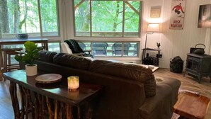 Een gezellige woonkamer met een groot raam, een houten tafel, een bank en een open haard.