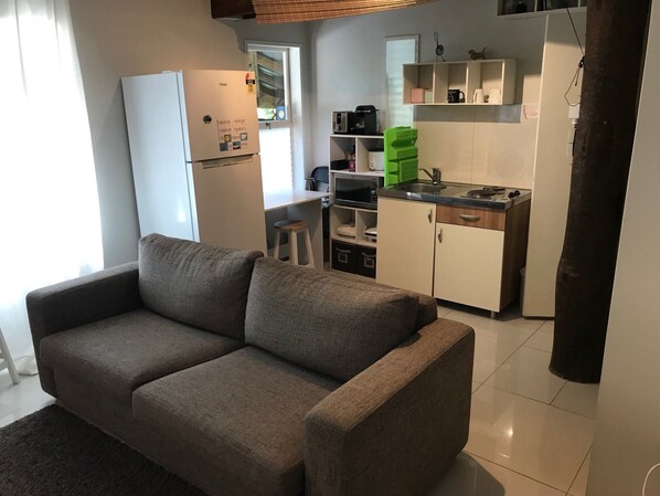 A compact living space with a sofa, kitchenette, and a small dining area.