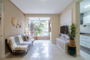 A modern living room with a sofa, a TV, and a potted plant. - Apart With Barbecue 600m From the Beach Rpn0101 (Florianópolis)