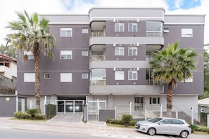A multi-story residential building with balconies, a gated entrance, and a parked car. - Apart With Barbecue 600m From the Beach Rpn0101 (Florianópolis)