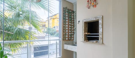Une cuisine avec une fenêtre, une plante suspendue et un élément décoratif en forme de coquillage accroché au mur.