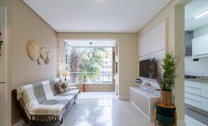 A modern living room with a sofa, a TV, and a potted plant. - Apart With Barbecue 600m From the Beach Rpn0101 (Florianópolis)