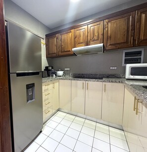 A kitchen with wooden cabinets, a stainless steel refrigerator, a microwave, and a coffee maker. - Aparts4Days 1-Bedroom Loft in Downtown Miraflores Near the Malecón (Lima)