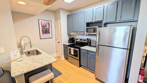 A modern kitchen with granite countertops, stainless steel appliances, and grey cabinetry.