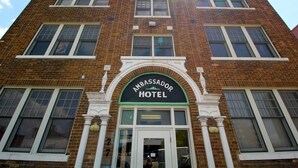 A brick building with a sign reading "Ambassador Hotel" above the entrance.