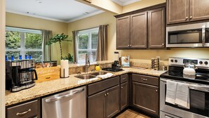 Una cocina moderna con armarios de madera oscura, electrodomésticos de acero inoxidable y encimera de granito.