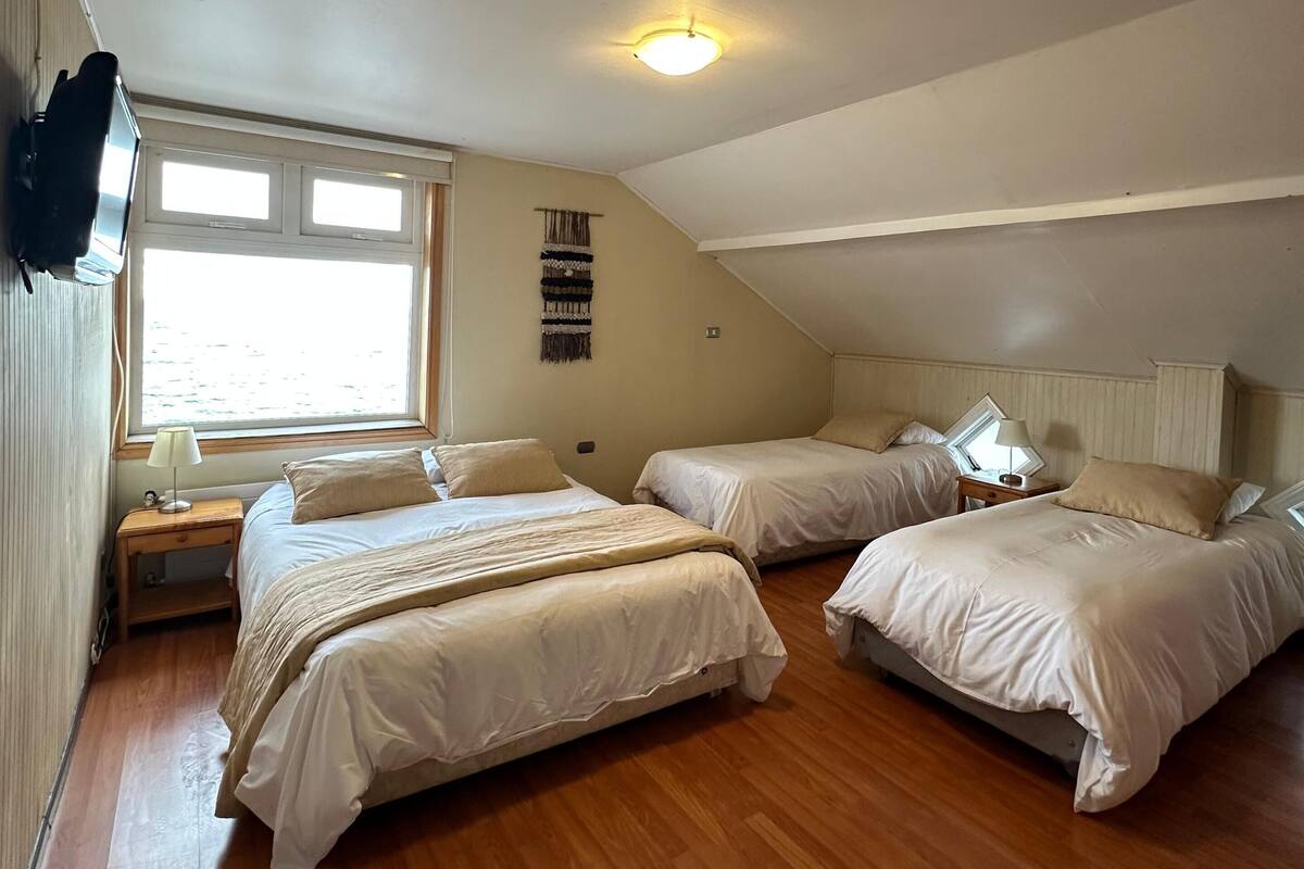Ein Zimmer mit zwei Betten, einem Fenster, einem Wand-Fernseher und einer Deckenleuchte.