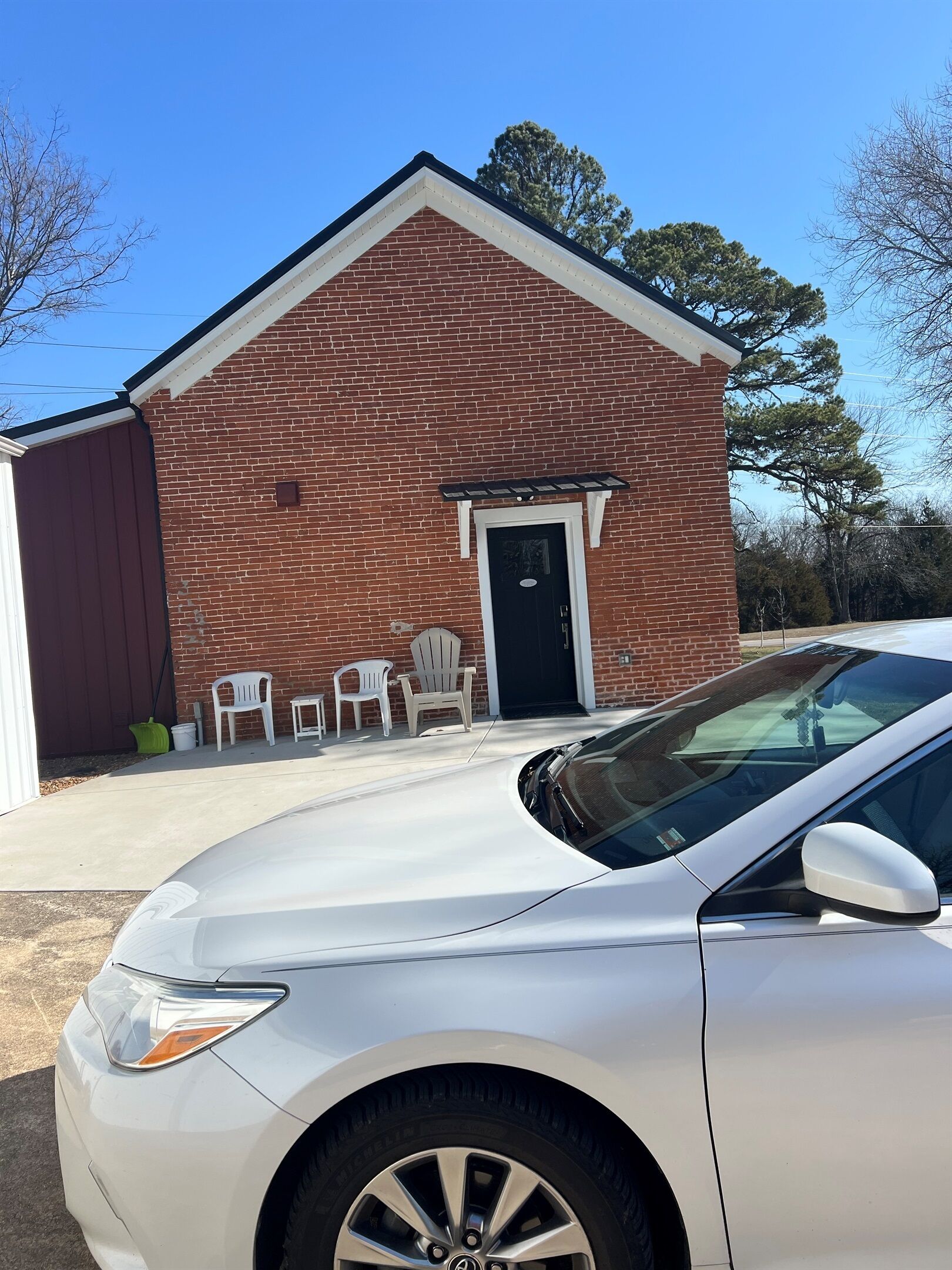 A building with a red brick exterior, a black door, and a white garage door.