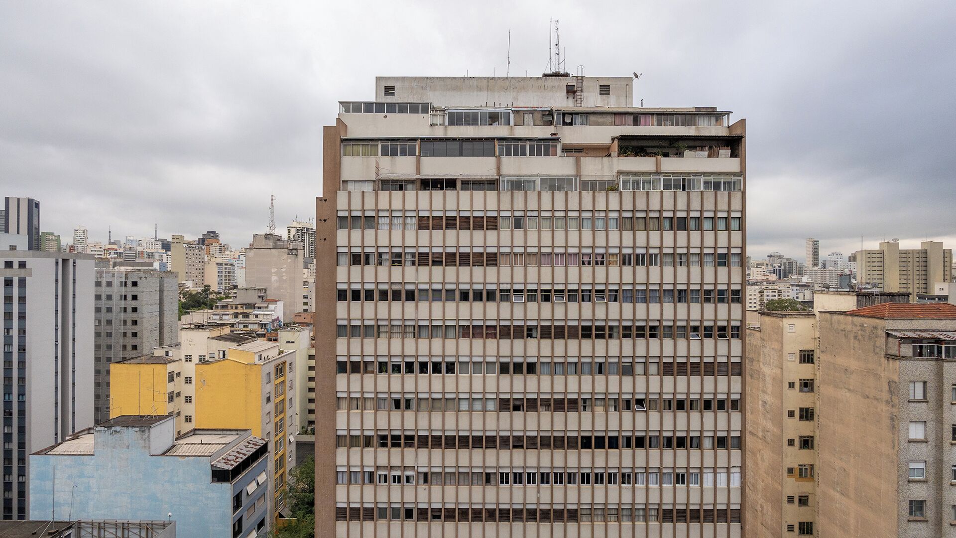 A multi-story building with a grid-like facade, surrounded by other buildings in an urban setting.