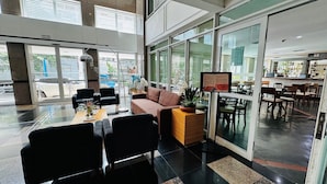 Un hall amplio con zona de estar, un mostrador de recepción y vistas al exterior.