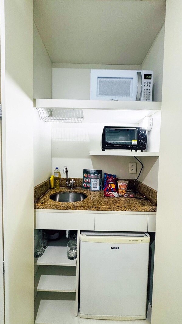 A compact kitchenette with a microwave, toaster, and a small refrigerator.