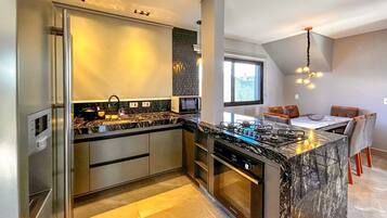 Cozinha moderna com forno embutido, micro-ondas e fogão a gás. Há uma área de refeições com mesa e cadeiras.