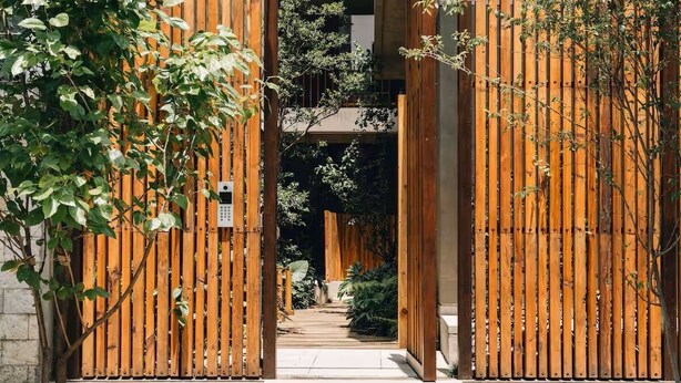 Een houten poort die leidt naar een gebouw met een modern ontwerp.